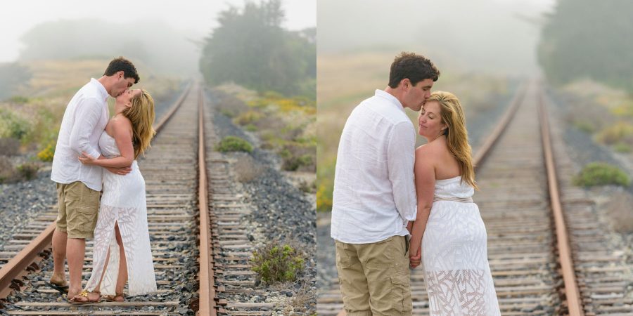 Close, newly engaged couple embracing with the railroad tracks disappearing into the misty distance - Davenport Beach Wedding / Engagement Proposal Photography - Julianna and Brian - photos by Bay Area wedding photographer Chris Schmauch www.GoodEyePhotography.com